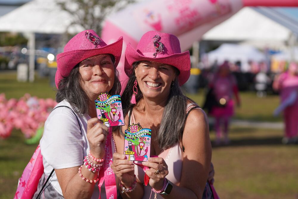 Two women in pink cowboy hats showing their medals