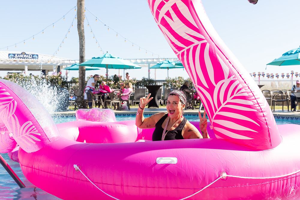 Woman waving from a giant inflatable flamingo in the pool