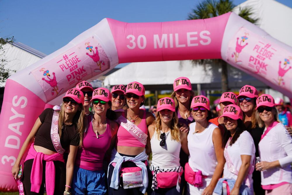 Team in pink trucker hats posing under the 30 Miles arch