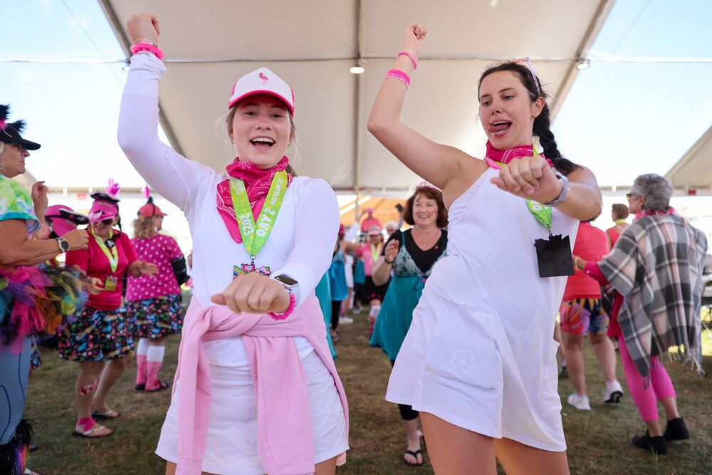 Two young women dancing in white outfits under the tent