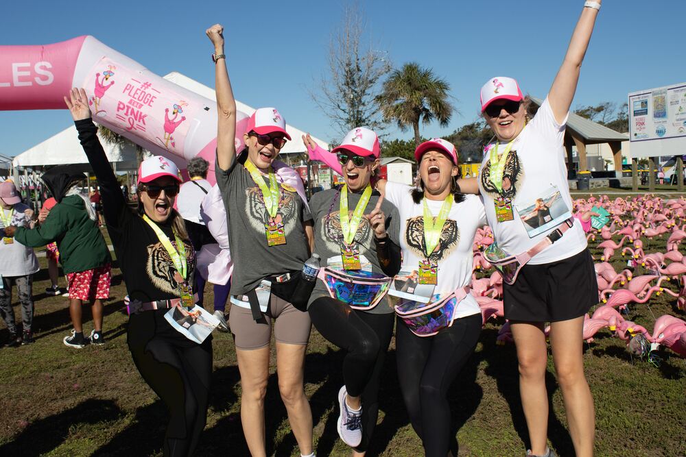 Five women with medals cheering beside the flamingo field