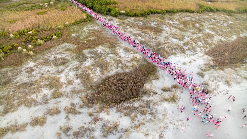 Aerial view of a long line of walkers crossing the dunes