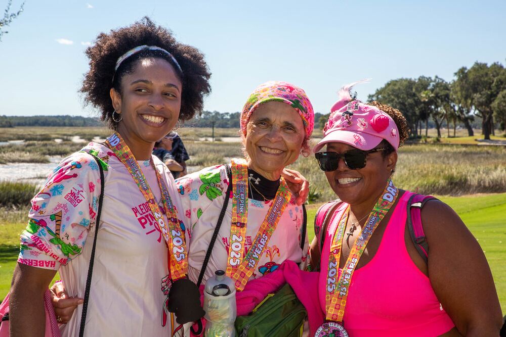 Three smiling women wearing their medals on a golf course