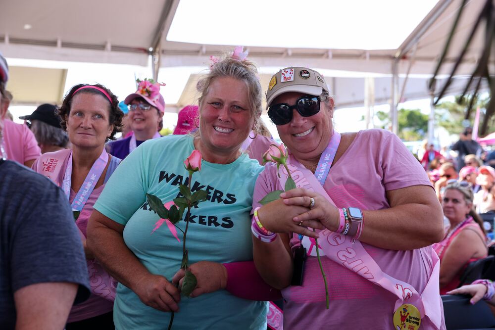 Two women holding pink roses and smiling under the tent