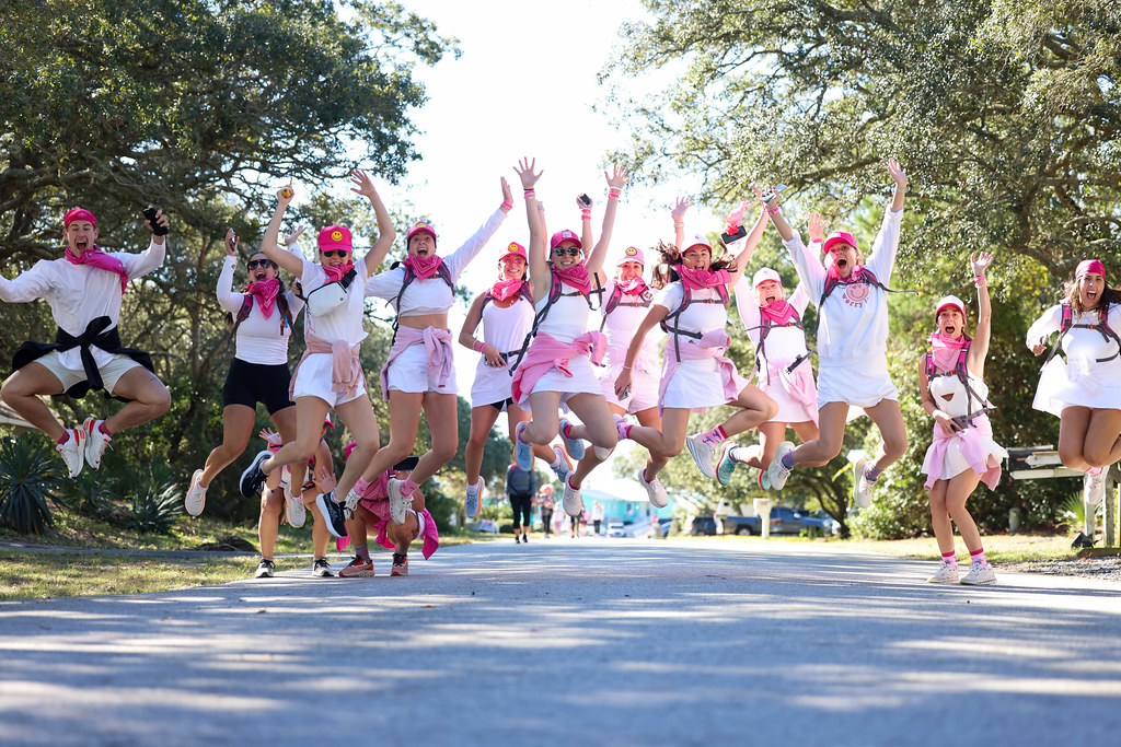 A team walking through the pink 30 Miles finish arch