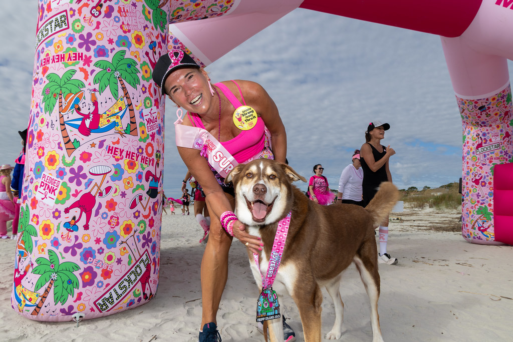 A survivor and her dog under the start arch on the beach
