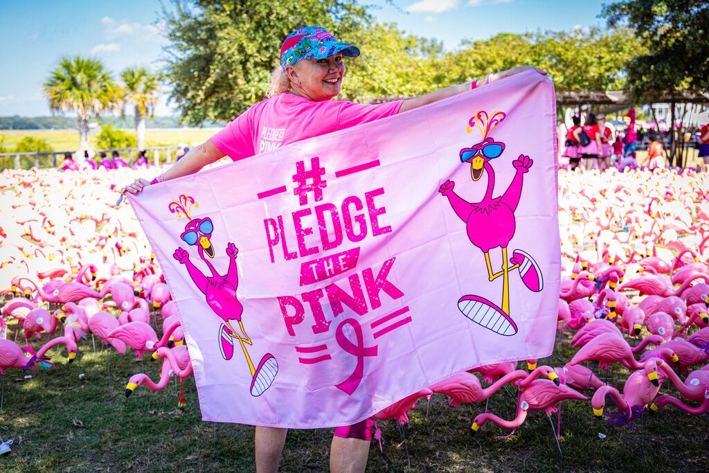 A FlockStar holding up a #PledgeThePink flamingo flag in the Flocks of Love field