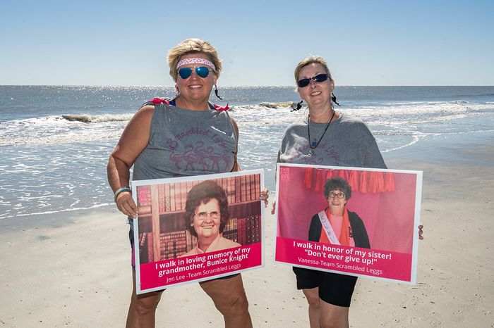 Two women holding memorial and tribute boards on the beach