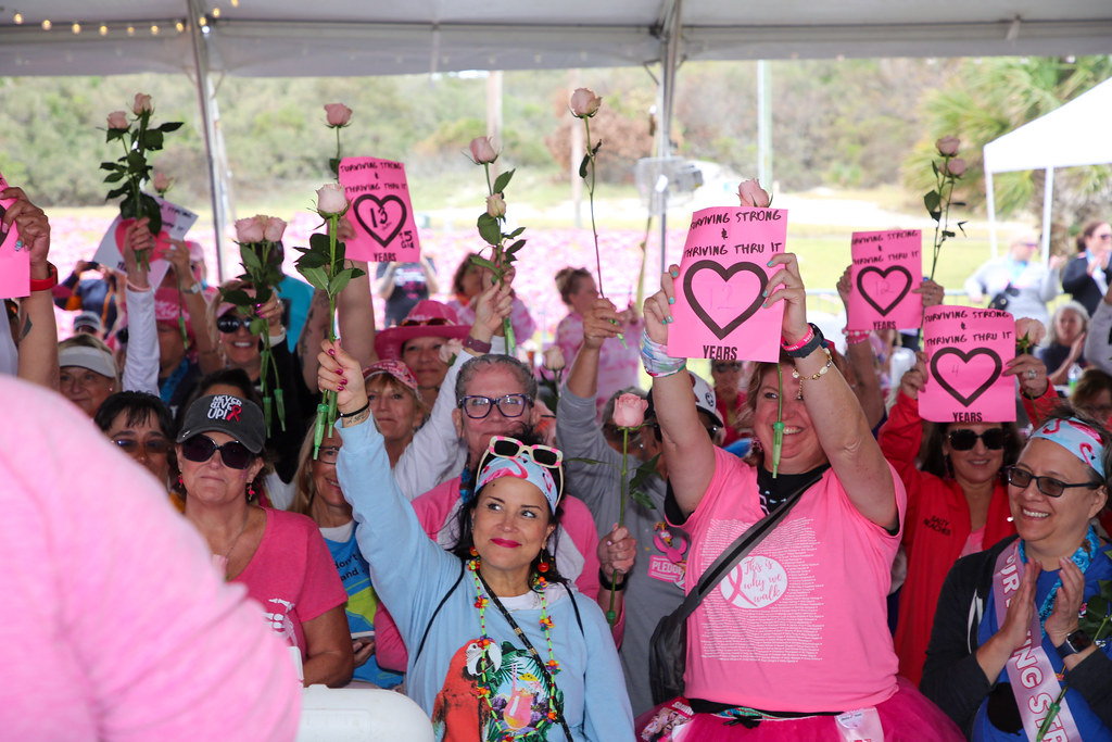 Survivors holding roses and pink signs counting their years of surviving strong and thriving thru it