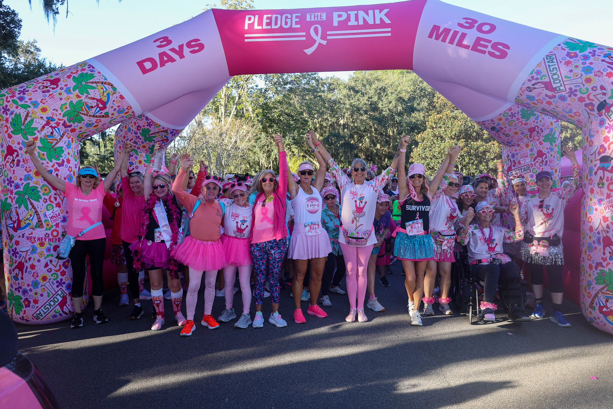 FlockStars with arms raised under the Pledge the Pink start arch